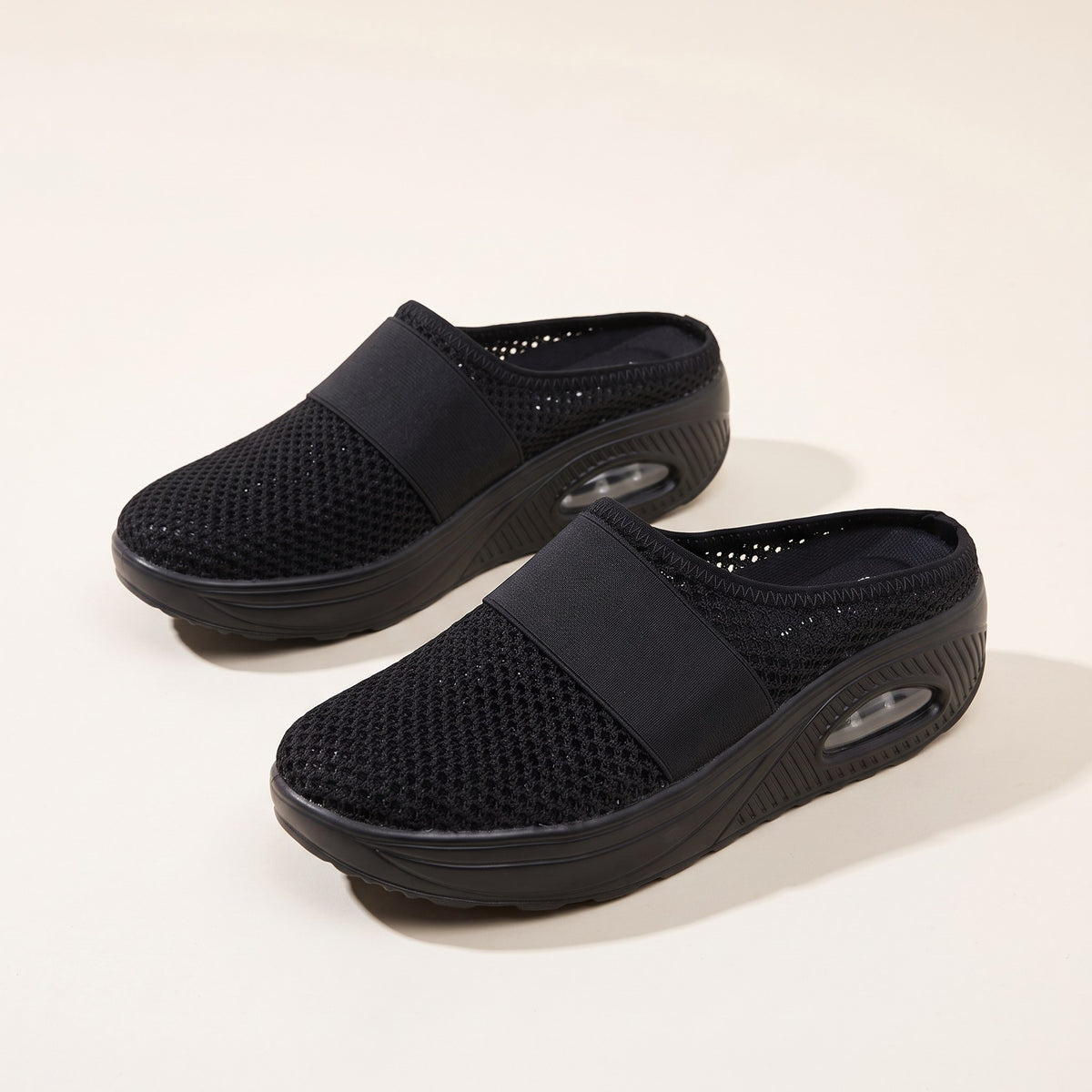 Backless cushioned slippers with air sole on a plain background